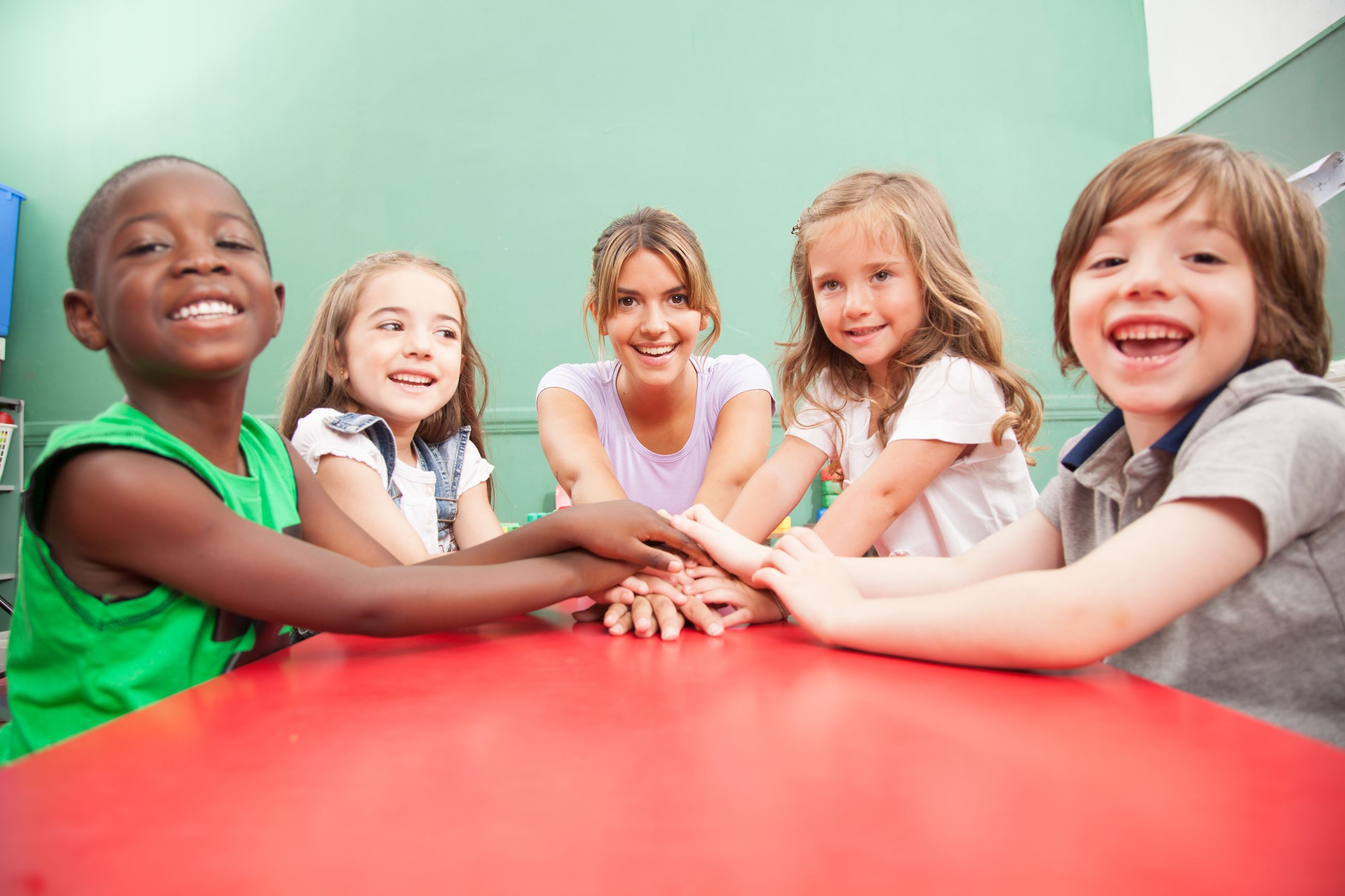 teacher-and-children-with-hands-together-SBI-301098331
