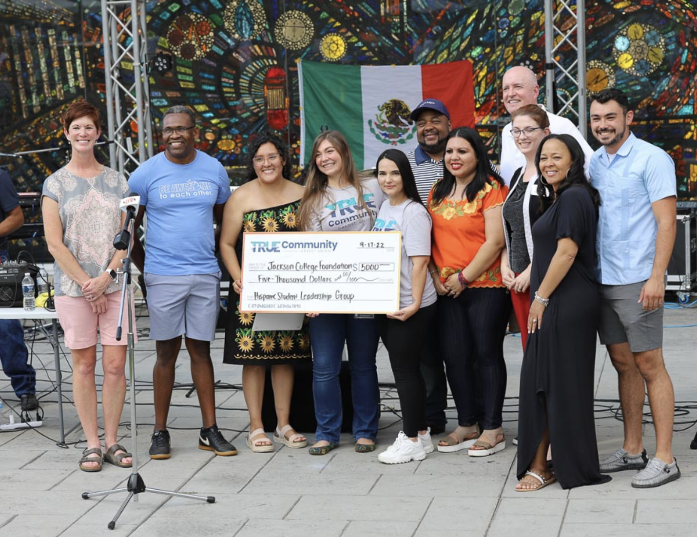 A group of men and women pose with a large check during the 2022 Hispanic Heritage Festival