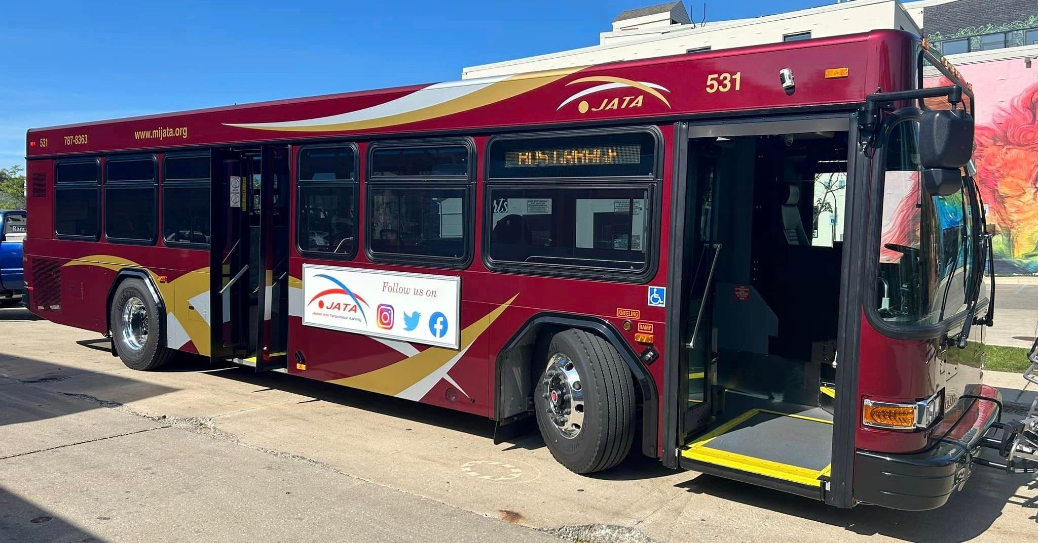 A red public transportation bus parked on a curb 