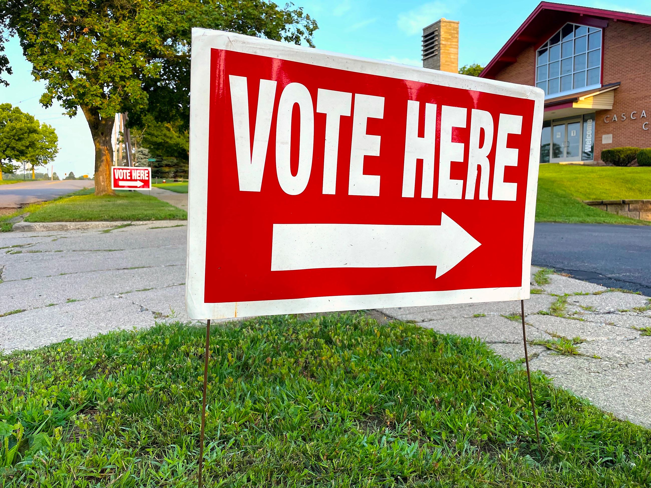 A red sign with white letters that says vote here 