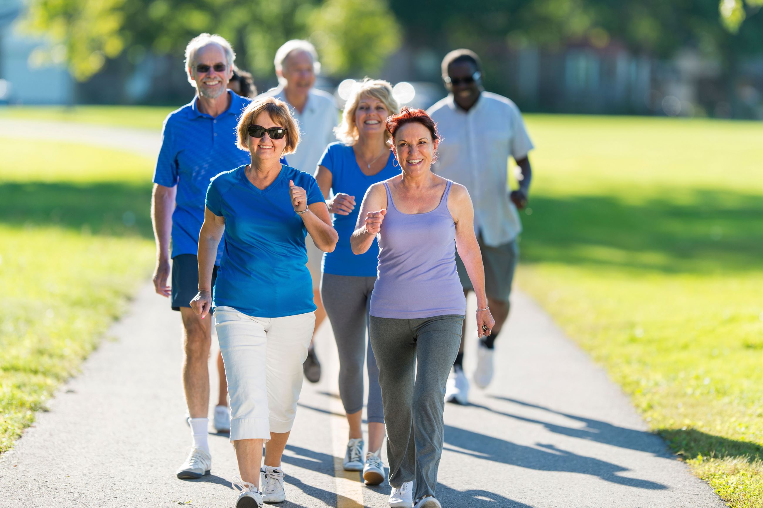 a group of men and women walking through a park smiling 
