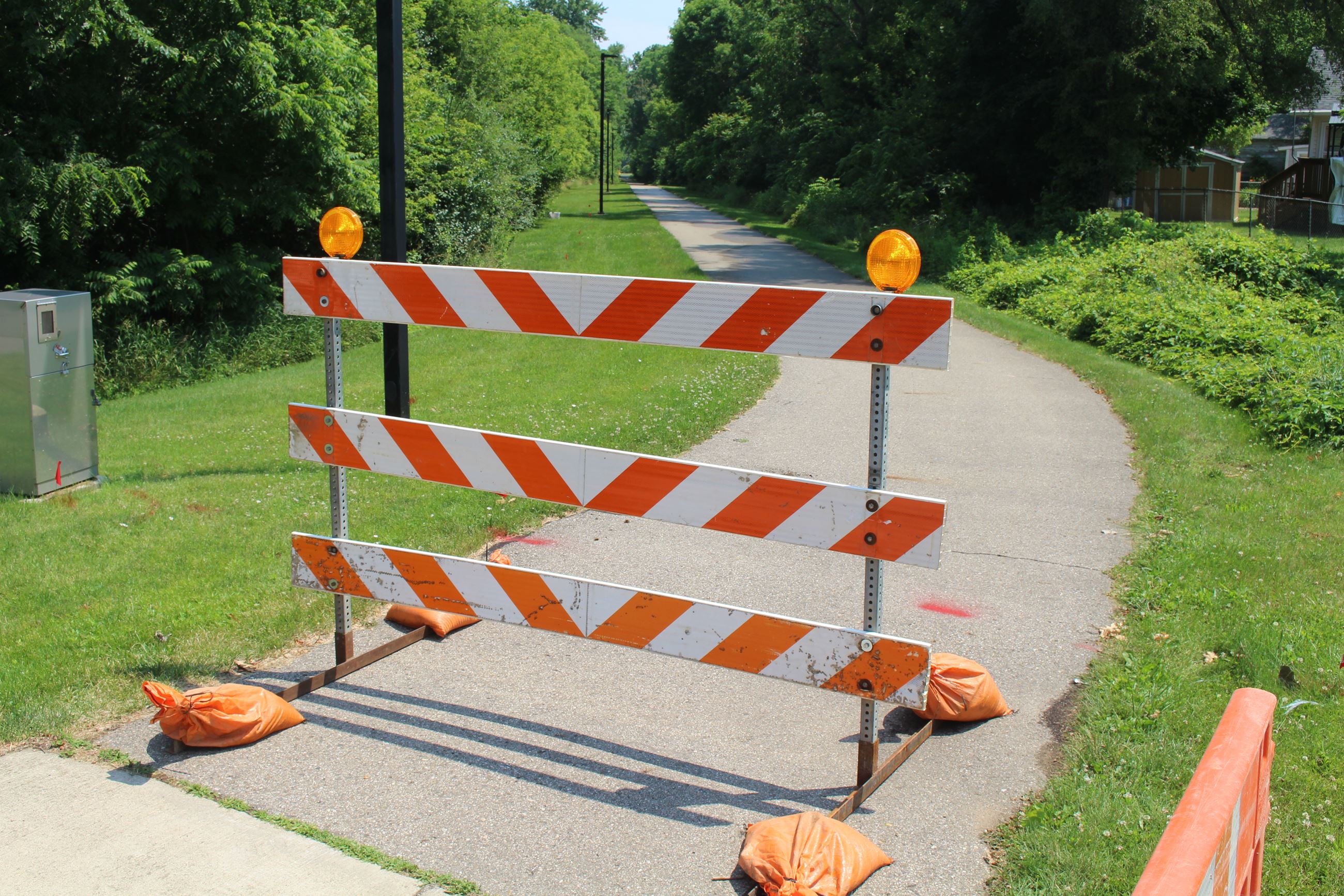 A baricade closes off a paved pedestrian trail 