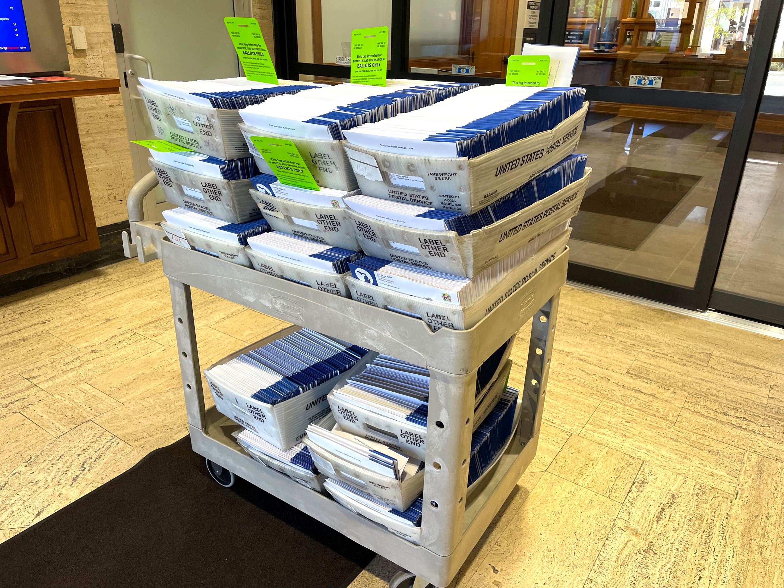 A cart full of absentee ballot envelopes displayed in a lobby 