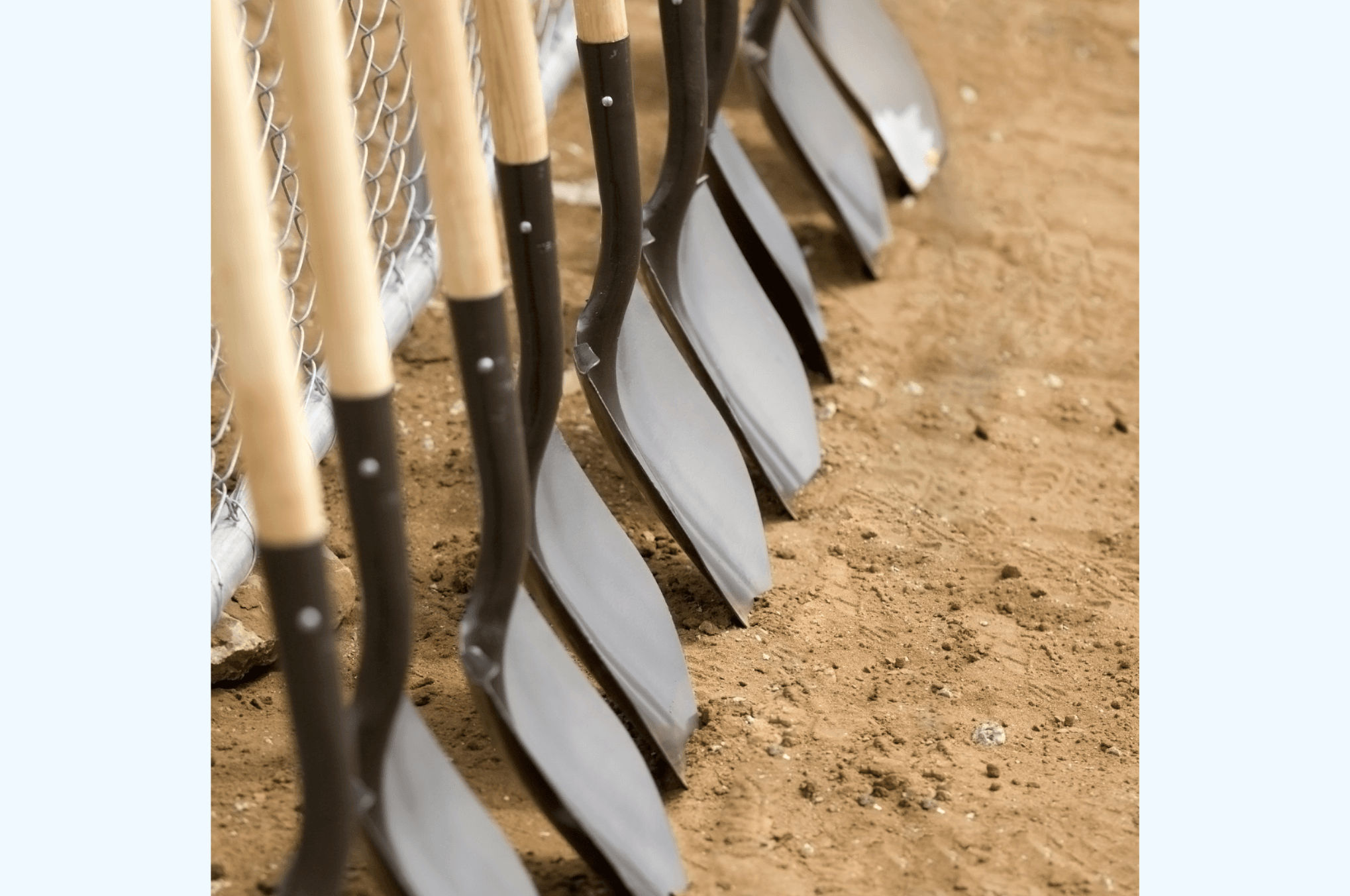 A line of shovels in dirt 