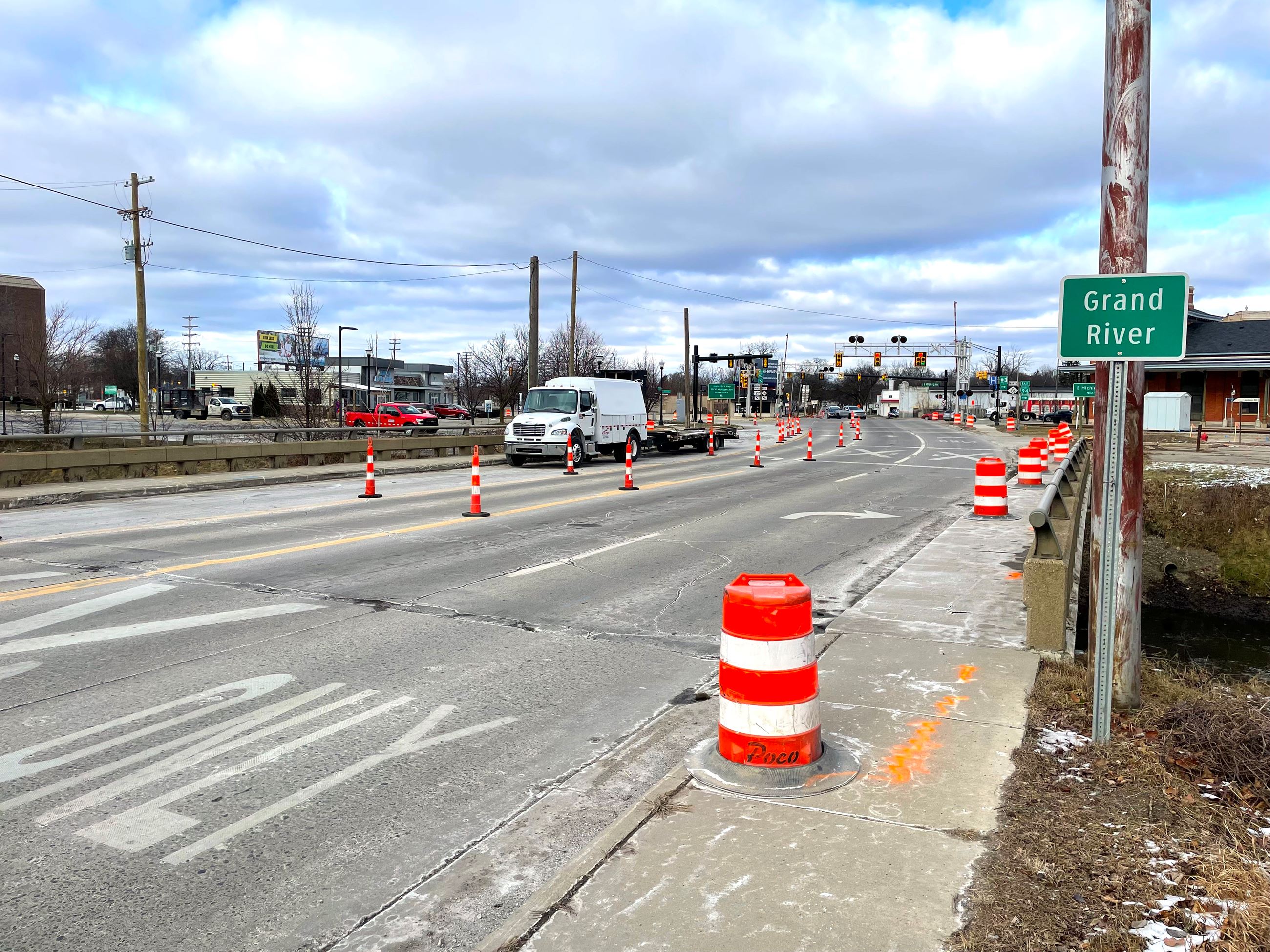 It's winter time. A photo of a bridge with cars passing by construction equipment. 
