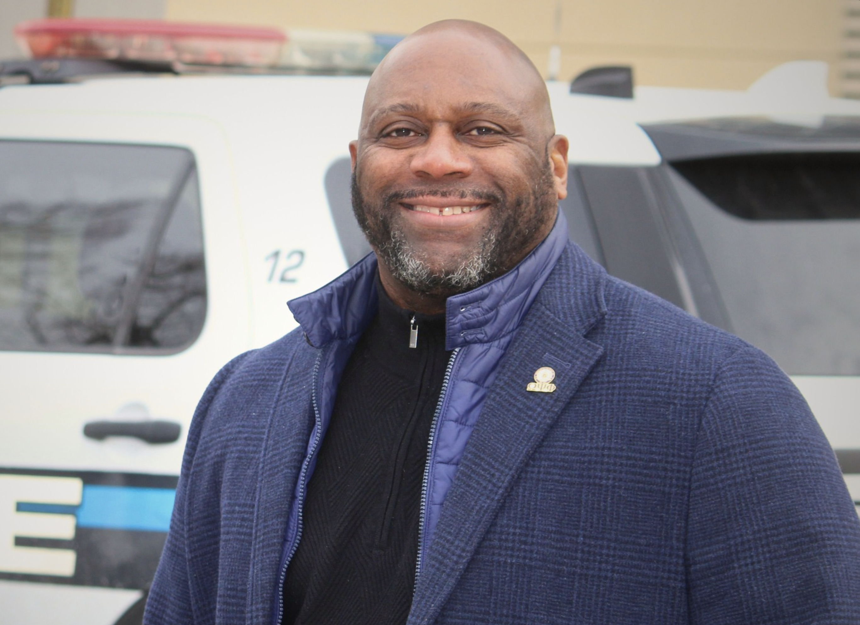 An man smiles standing next to a police car 