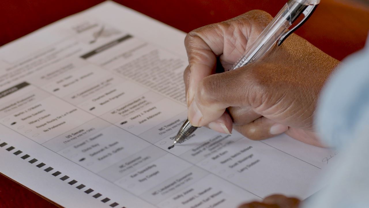 Hand filling out an absentee ballot 