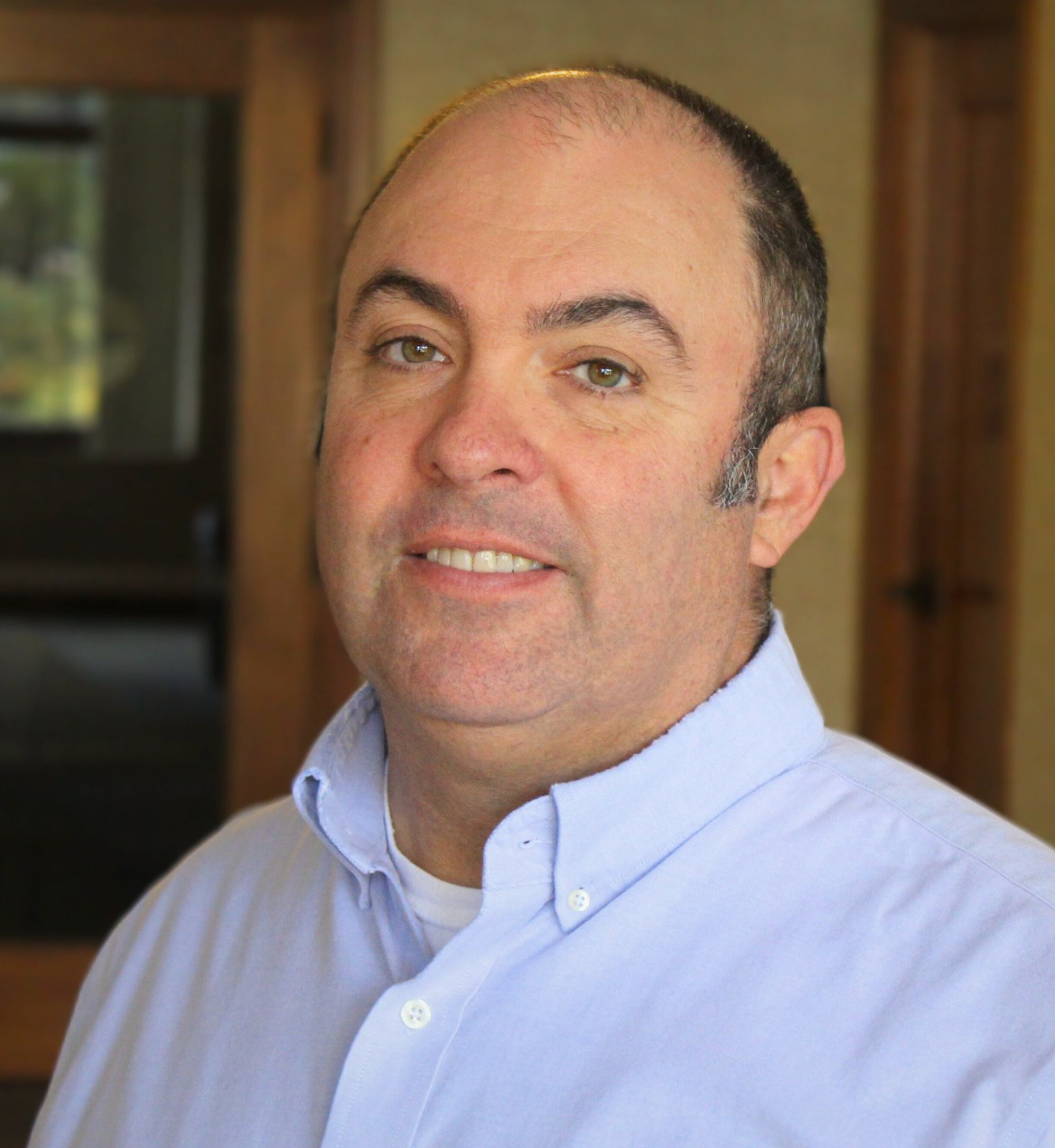 A white male smiles wearing a blue shirt 
